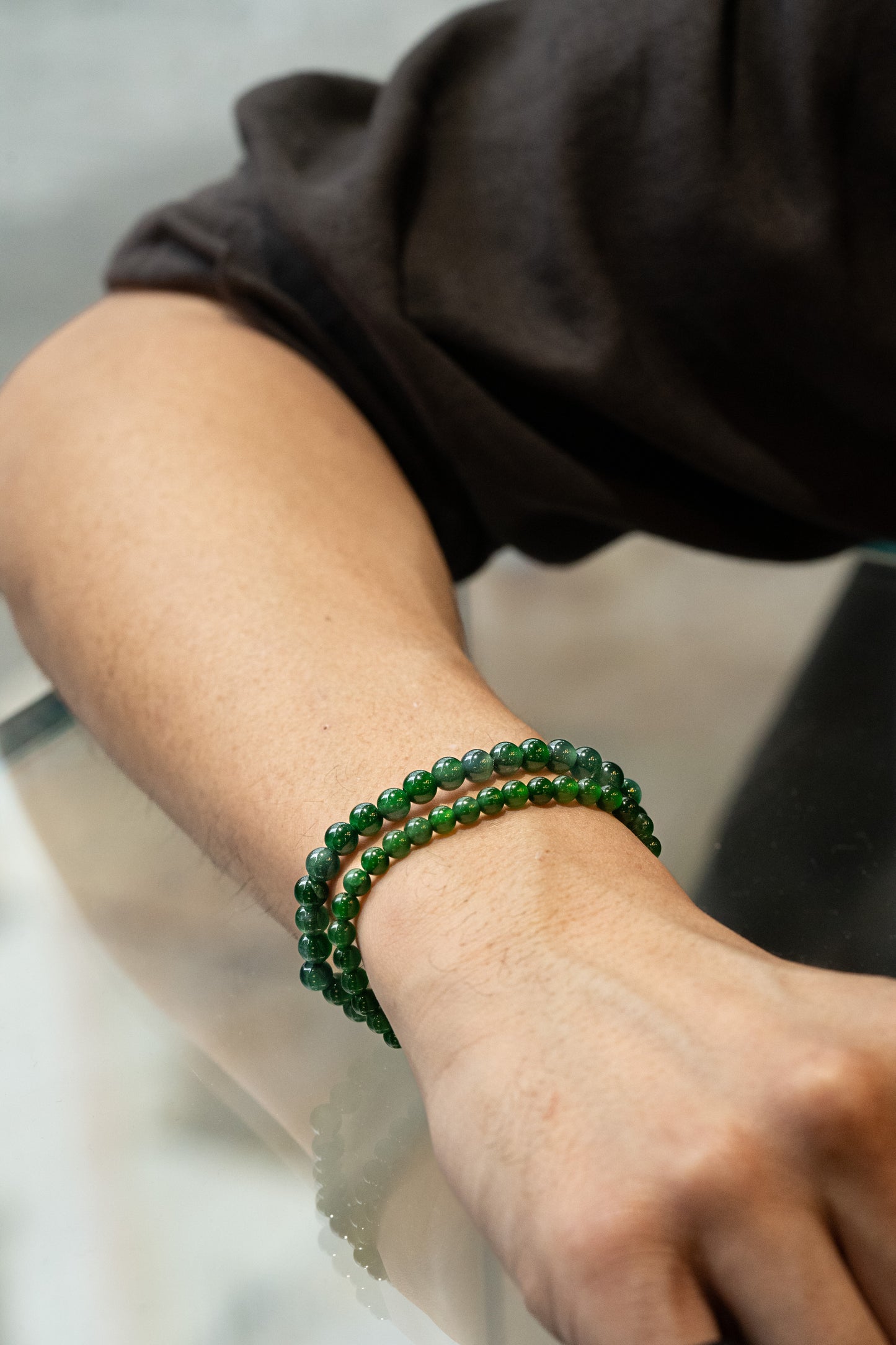 A person's forearm wearing a bluish green jadeite bead bracelet