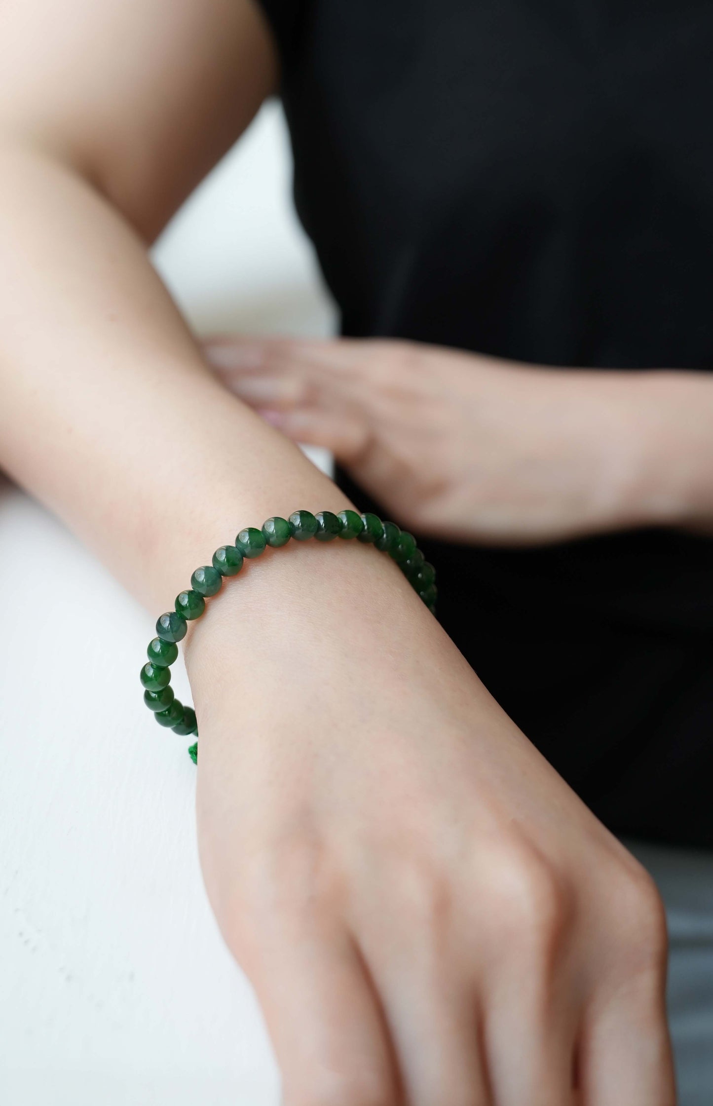 Close-up of a hand wearing a green jadeite bead bracelet