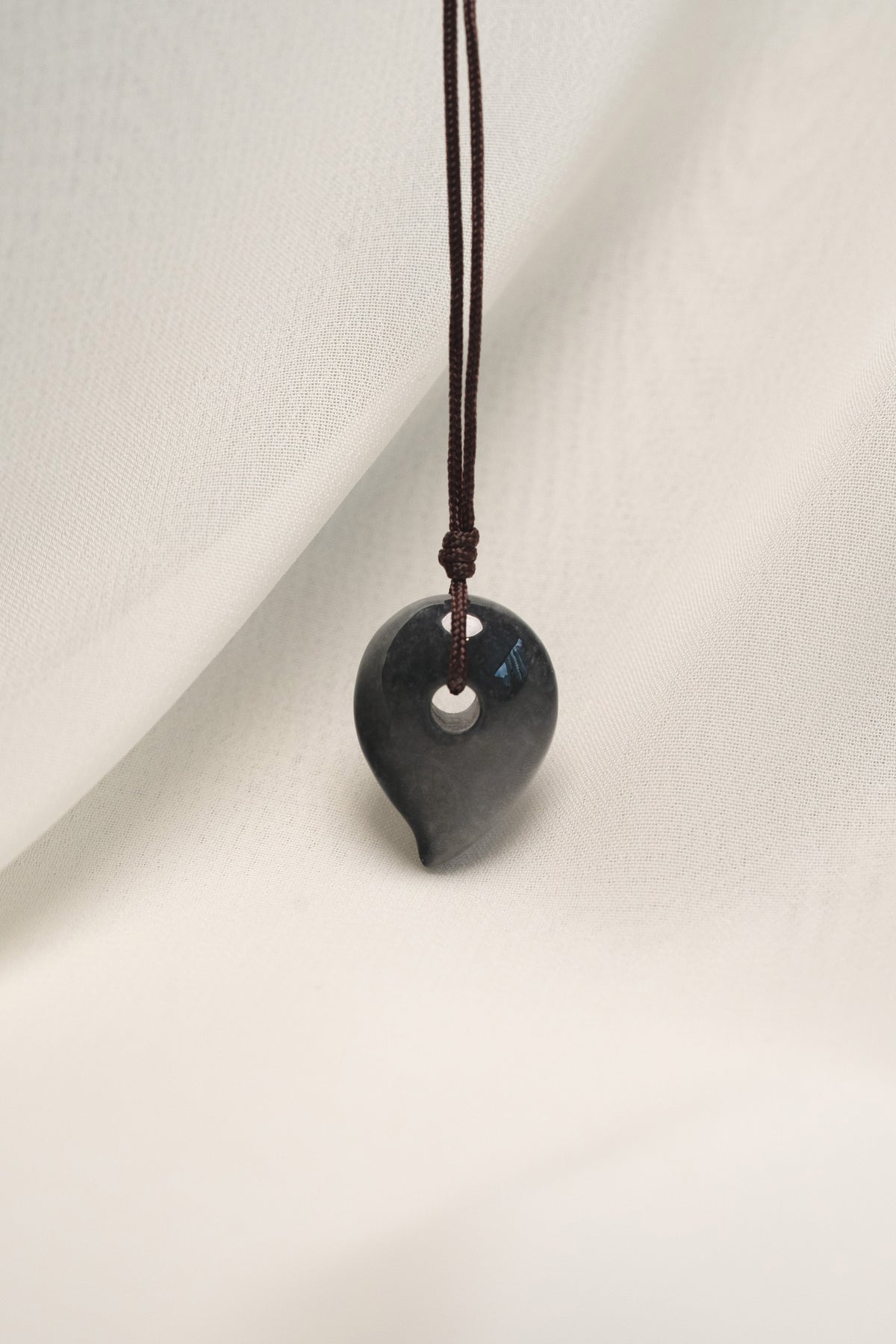 Black Jadeite Magatama Pendant with White patches hangs on a String