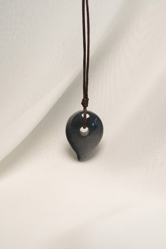 Black Jadeite Magatama Pendant with White patches hangs on a String