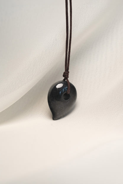 Black Jadeite Magatama Pendant with White patches hangs on a String
